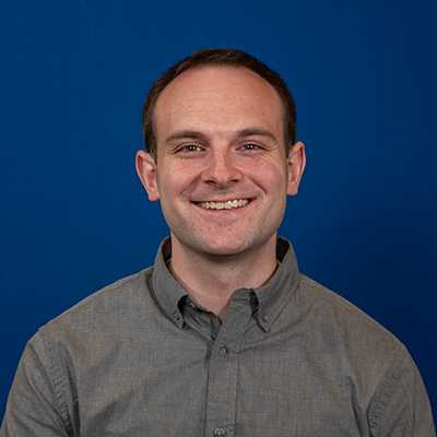 A white, male-appearing individual with short brown hair smiling at the camera.
