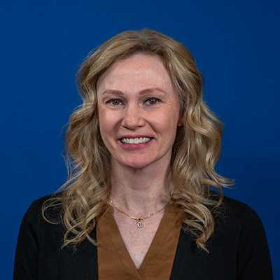 A 40-year-old white woman with blonde curly hair wearing a black cardigan.